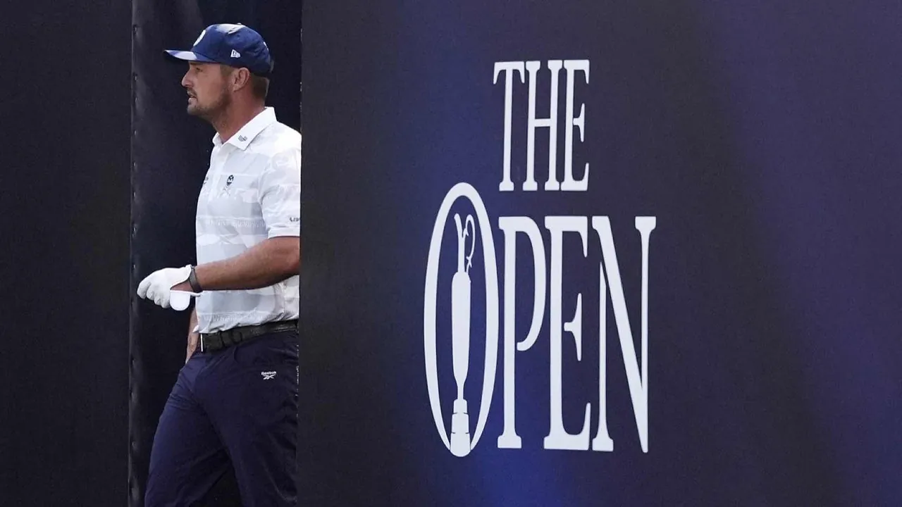 A golfer in a white shirt and blue cap stands next to a large sign that reads THE OPEN with a golf tee design inside the letter O.