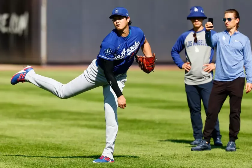 Los Angeles Dodgers' Shohei Ohtani, left, throws in the outfield.